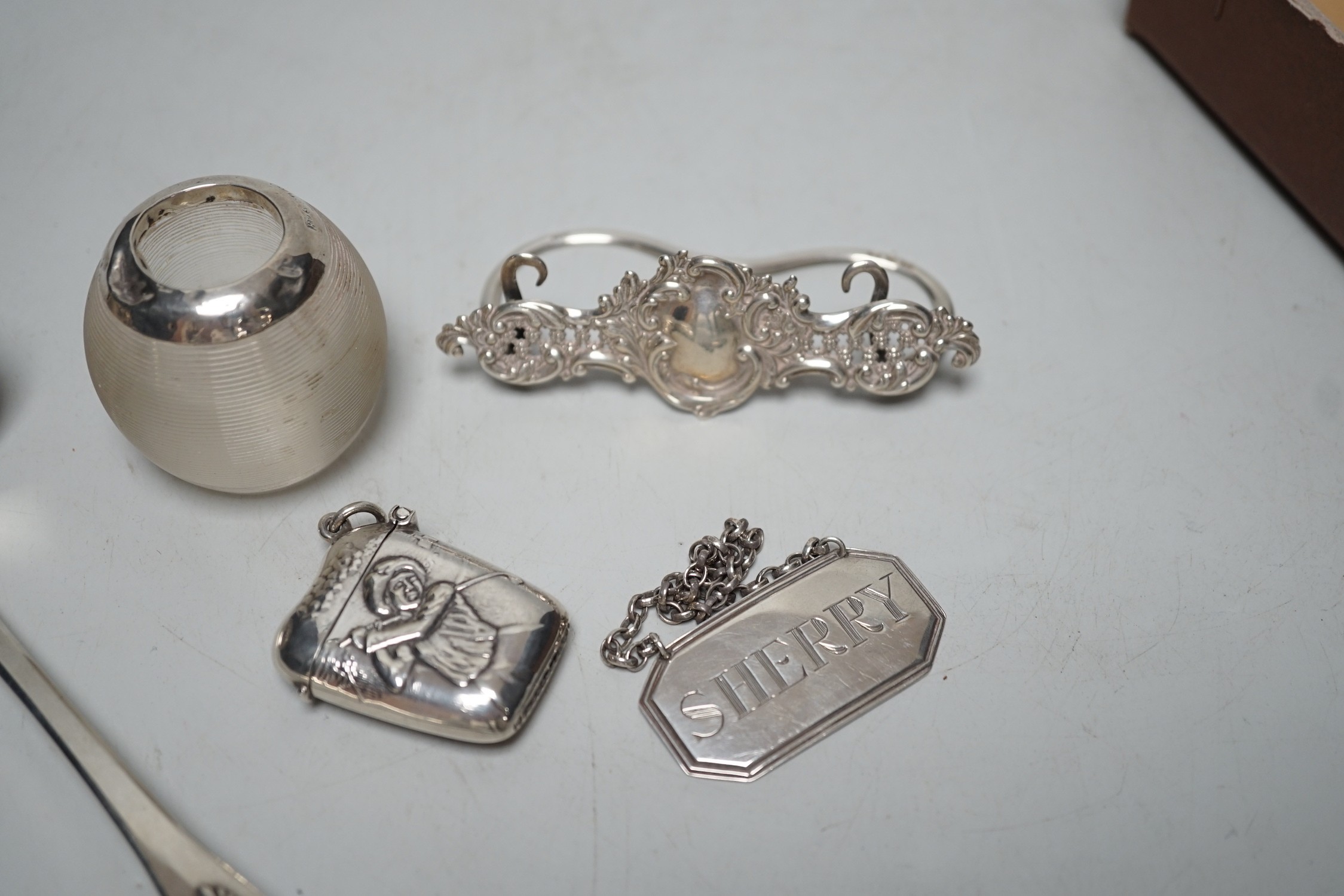 A small Edwardian silver mounted ribbed glass match tidy, height 40mm, a Georgian Scottish Kings pattern sauce ladle, a silver menu holder, modern silver wine label and a 925 golf related vesta case.